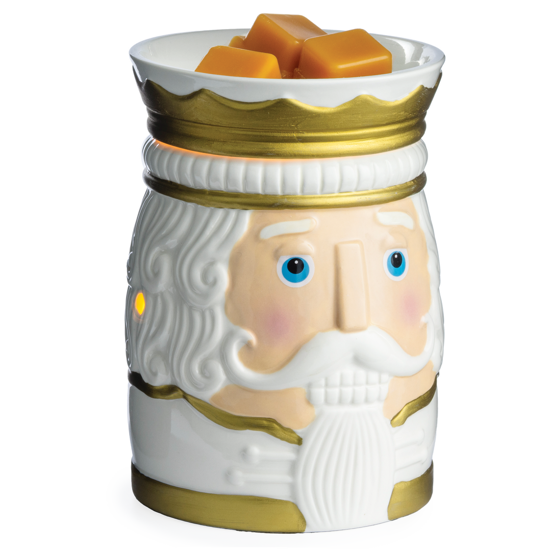 Freigestellte Nutcracker-Duftlampe in Weiß und Gold mit Nussknackergesicht und orangefarbenen Wachswürfeln in der Schale.